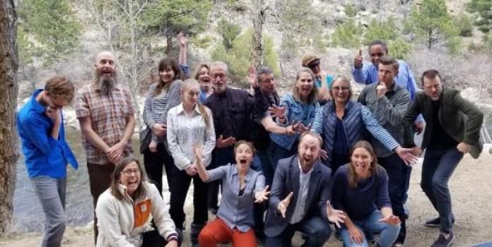 Group of workshop participants gathered in a wooded area in Colorado