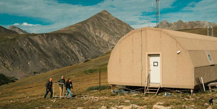 Three researchers outside of mountain research station