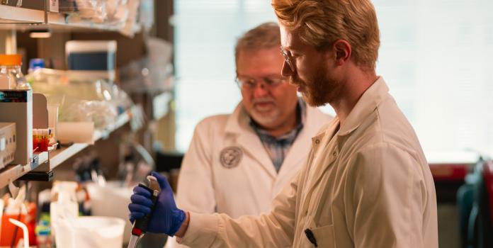 Two researchers study proteins in a lab