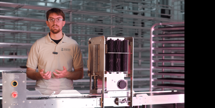 Max Knight standing next to Rooted Robotics equipment