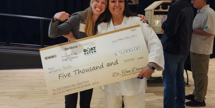 Two women hold an oversized check