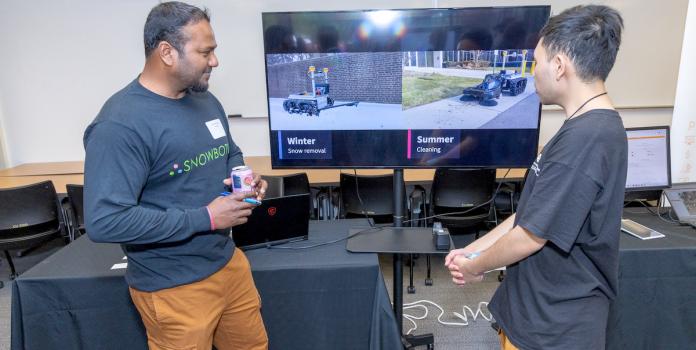 Two people discuss snow clearing robots