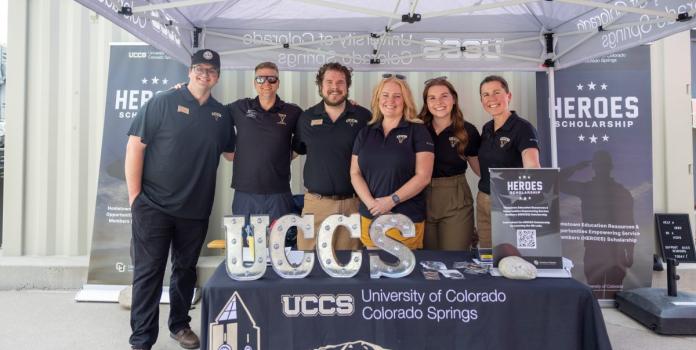 a group of men and women stand under a tent 