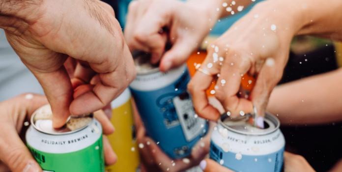 Hands cracking open cans of beer