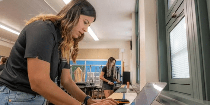 A female student sets up air testing equipment in a classroom