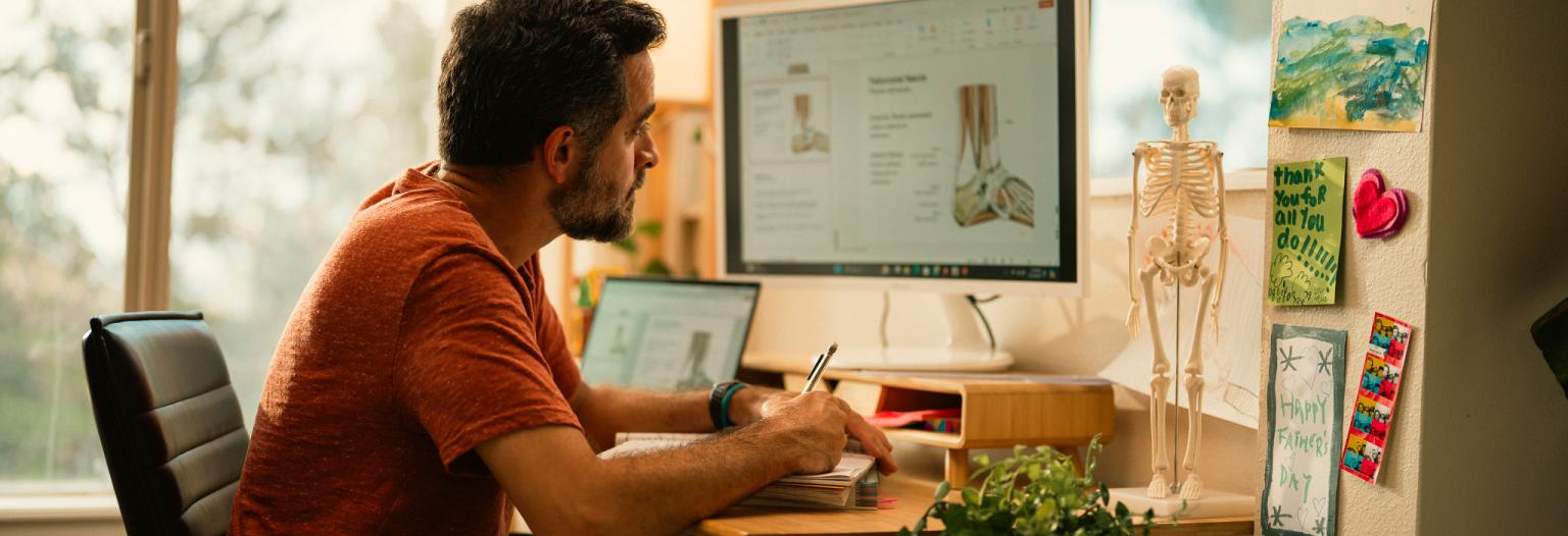 Man studying physical therapy on his computer at home