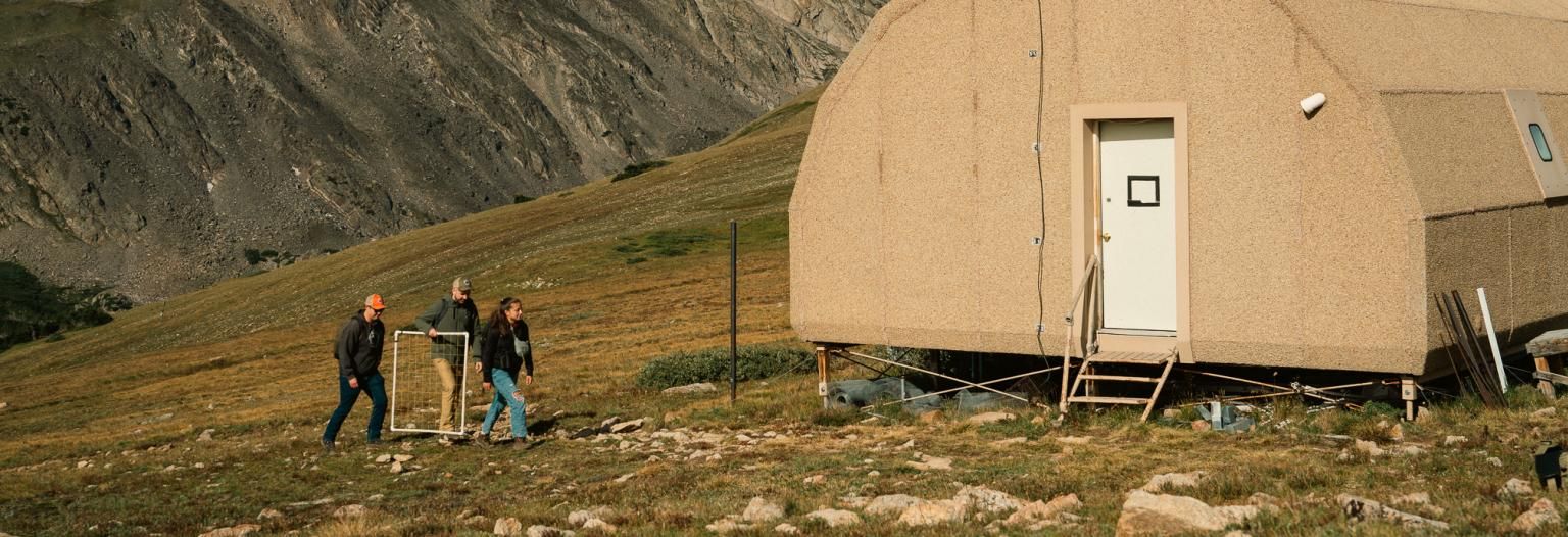 Three researchers outside of mountain research station