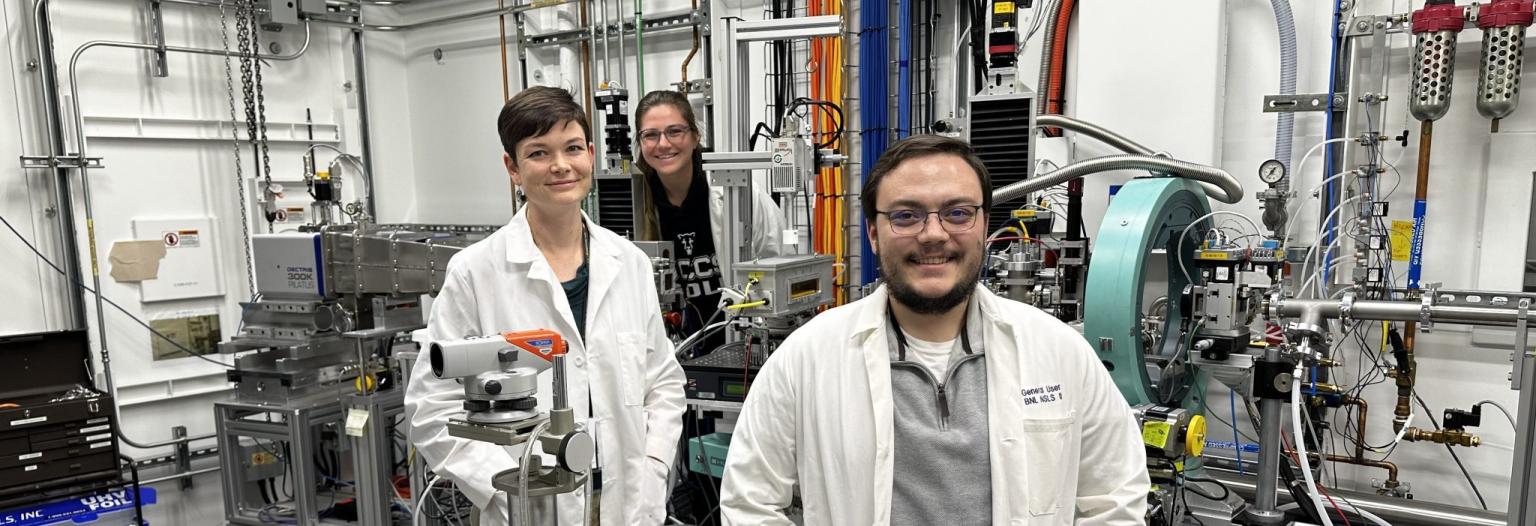 Three scientists standing amidst complex scientific machinery