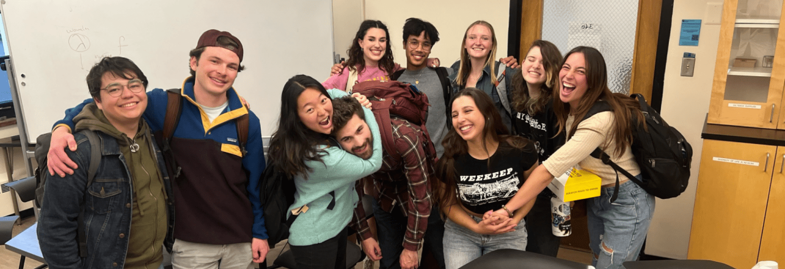 A group of college-age students poses for a picture in a classroom