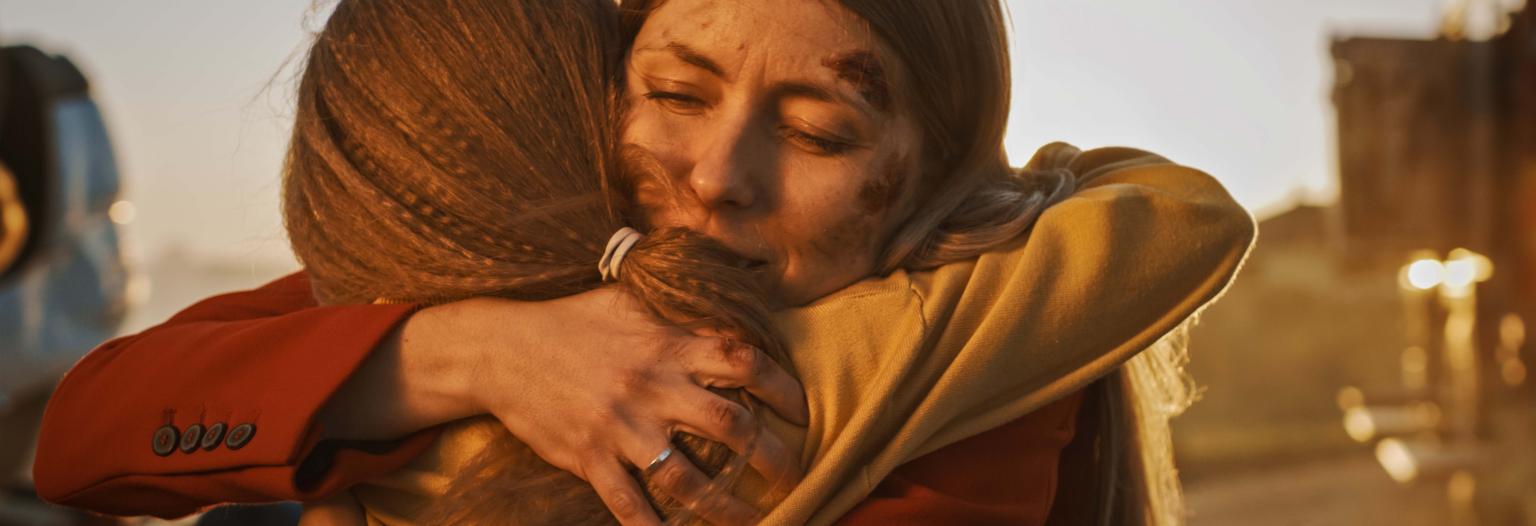 Two women hug each other in the midst of a natural disaster