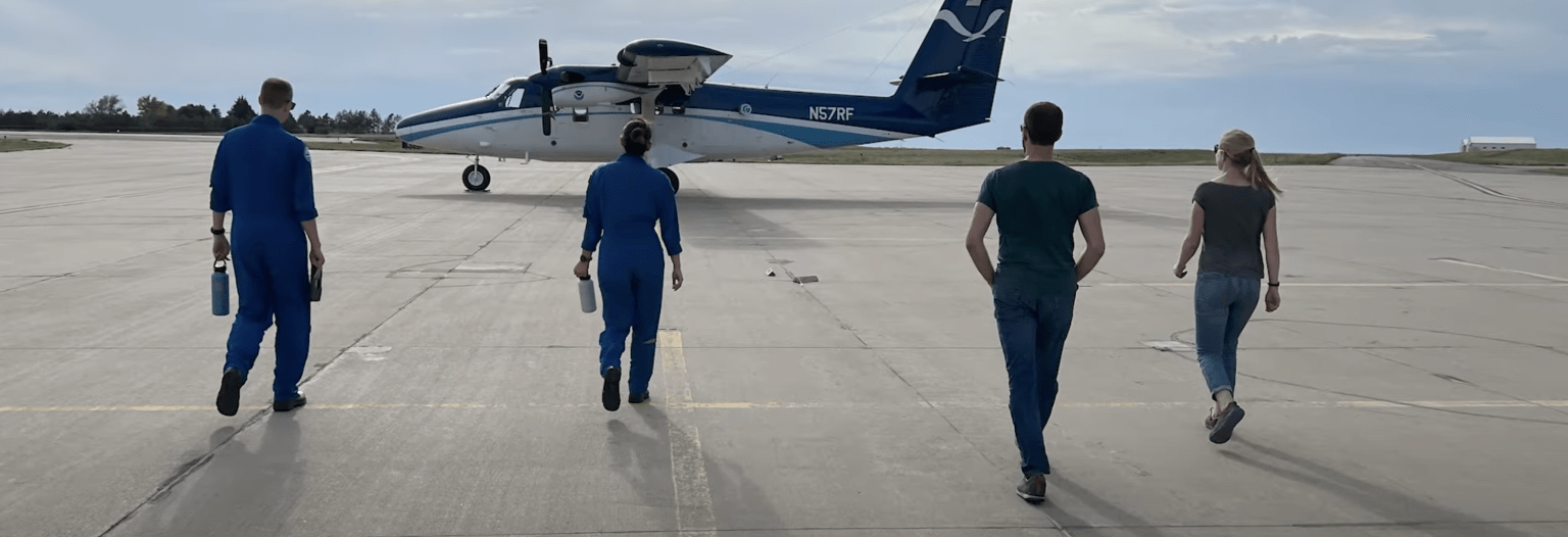 A group of 4 fire researchers walk towards a plane sitting on a runway