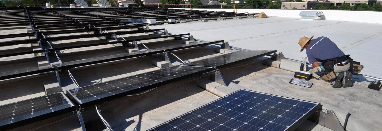 A man inspects solar panels on a roof