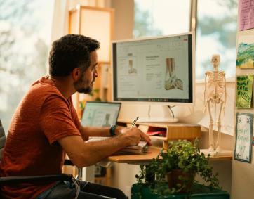 Man studies physical therapy on computer in his home