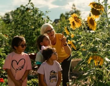 A woman shows children a sunflower garden