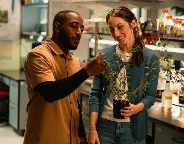 Two researchers study a firecracker plant in science lab