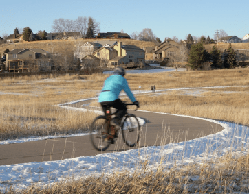 Cyclist riding down snowy path